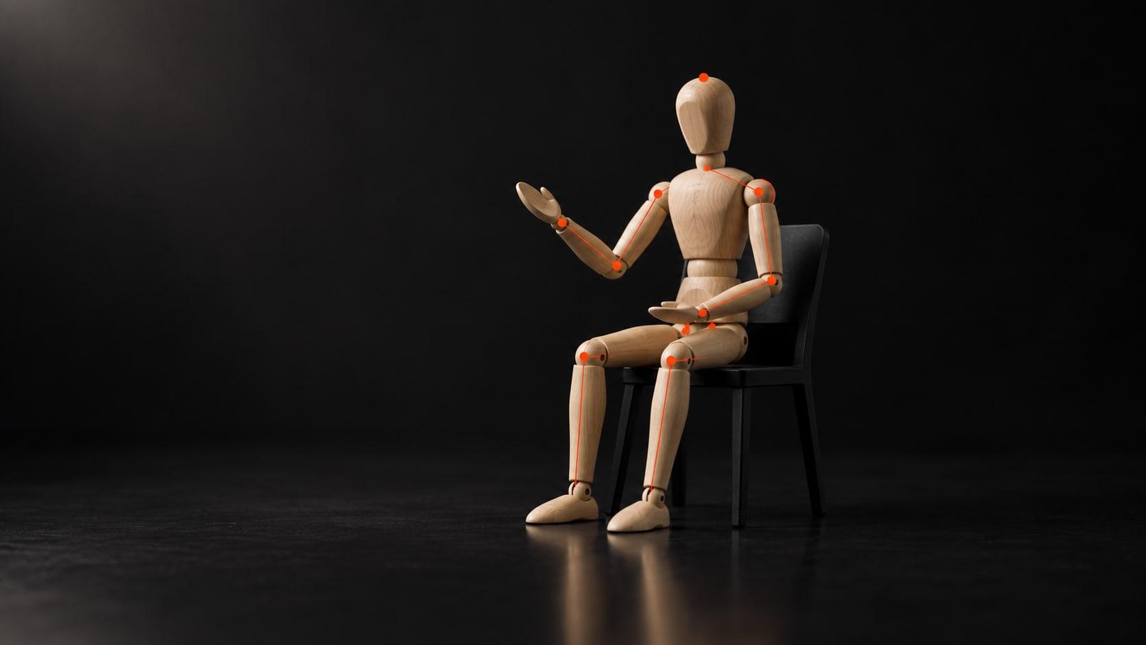 BodyTalk: a wooden mannequin seated as if in an interview, its joints marked with orange pose landmarks